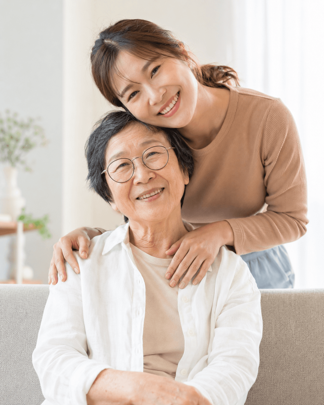 A younger woman embracing an older woman seated at home